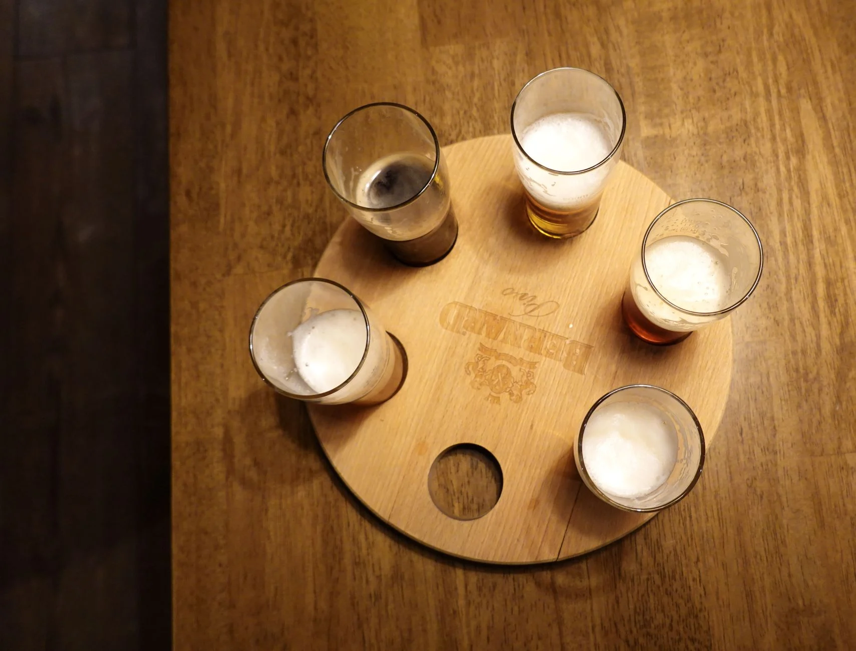 Bandeja de madera con varios vasos para una cata de cerveza