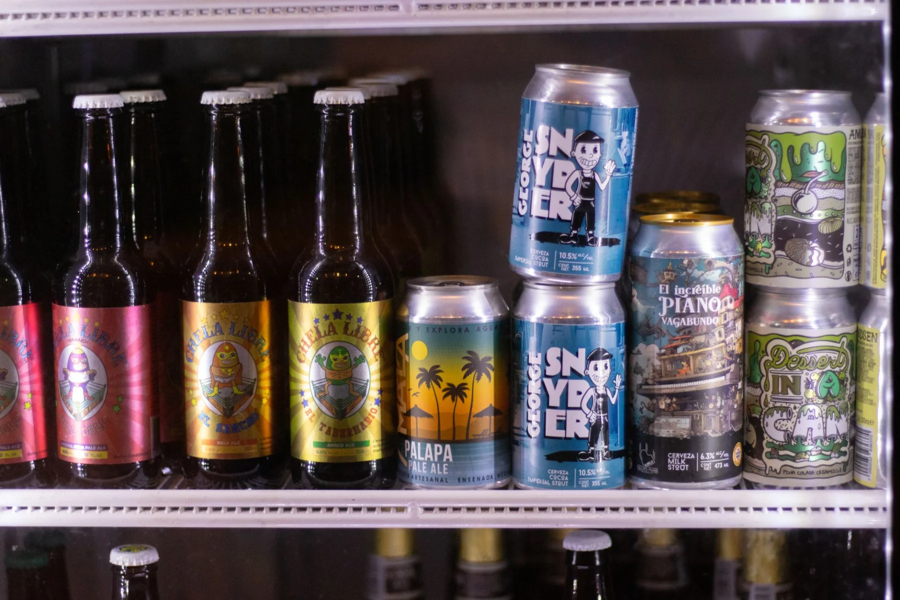 Mini nevera para cerveza con botellas y latas en un bar doméstico